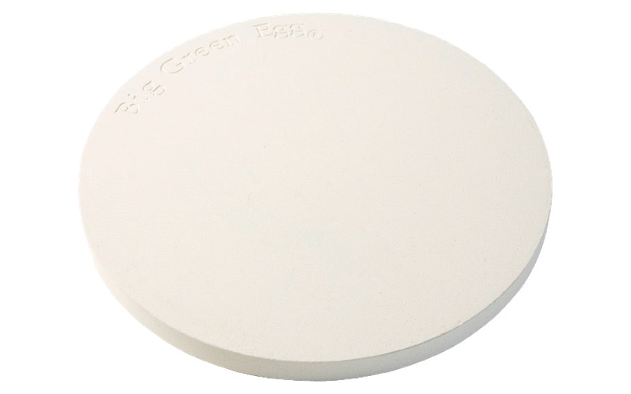 De Big Green Egg Pizza en Baking Stone heeft de vorm van een cirkel en is gemaakt van wit keramiek. Dit specifieke model is geschikt voor de Big Green Egg MiniMax, de Big Green Egg Small en de Big Green Egg Medium. De steen is schuin vanaf de bovenkant in beeld gebracht.