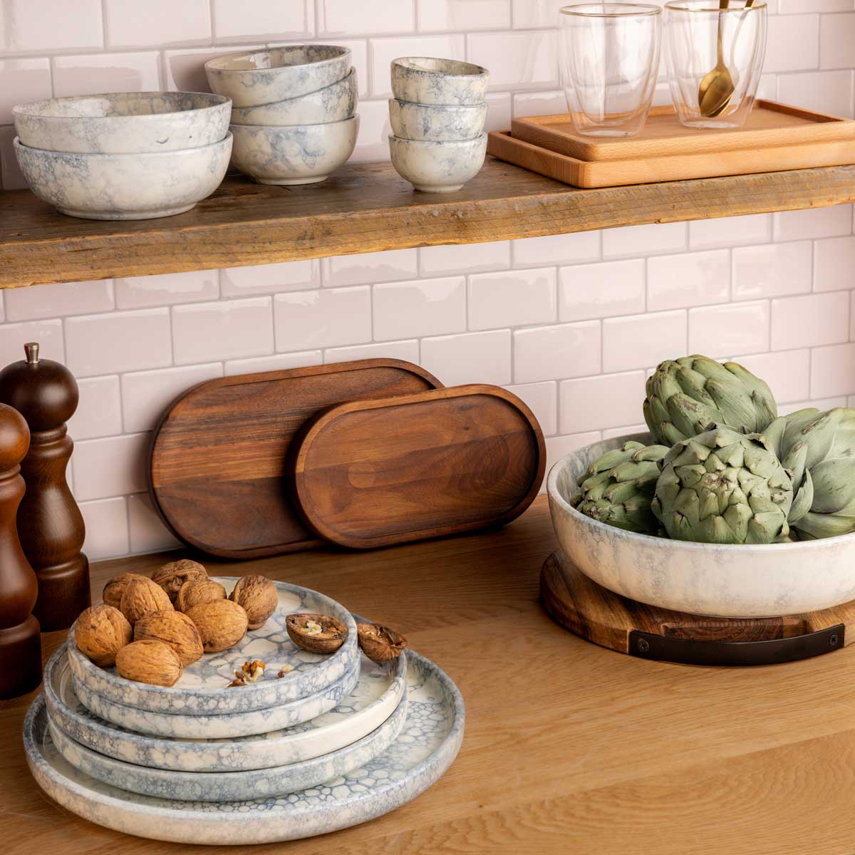 Een decoratieve setting in een keuken met borden en schalen in verschillende maten van de Espuma servies serie met de kleur grijs.