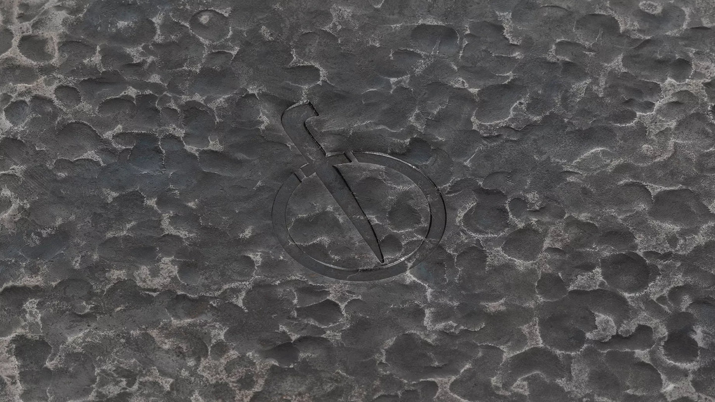 Een close-up van het het beeldmerk van het merk Forged, dat aan de onderkant van de pan is ingebrand.