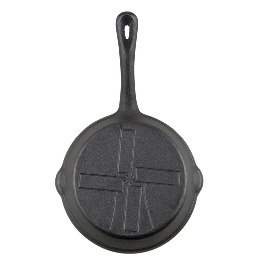 Dezelfde zwarte gietijzeren skillet aan de achterkant van bovenaf gefotografeerd.