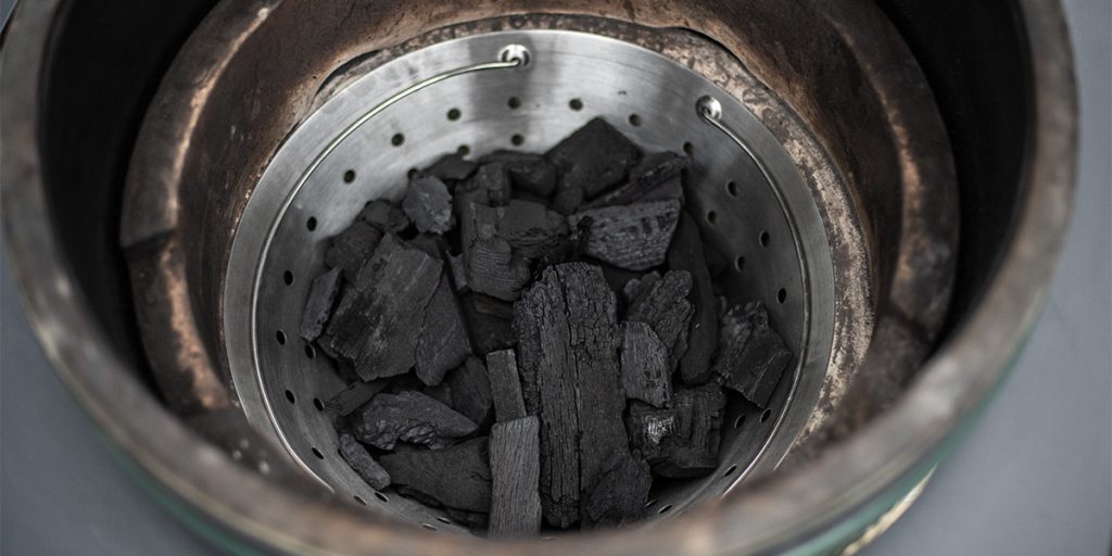 De gevulde houtskoolmand geplaatst in een Big Green Egg.