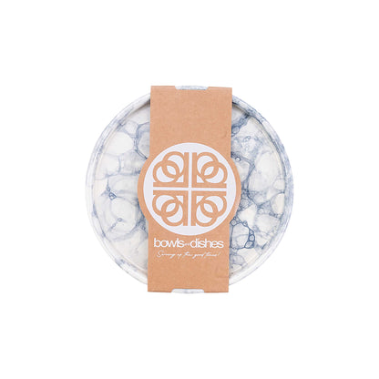 Handgemaakt aardewerken bord met een diameter van 18 cm tegen een witte achtergrond. Het bord is roomwit van kleur, heeft  een patroon van luchtbellen in verschillende grijstinten en is voorzien van de verpakking van Bowls & Dishes. Het bord is van bovenaf gefotografeerd.