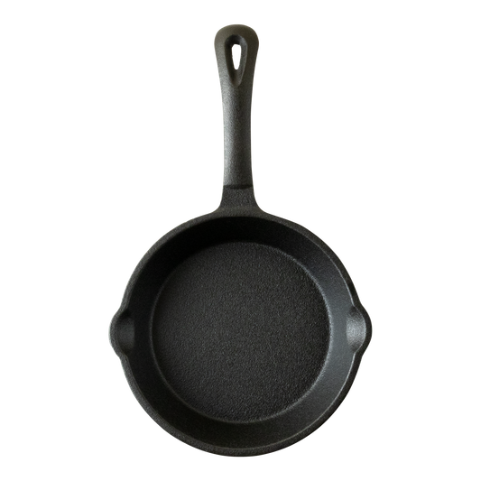 Zwarte gietijzeren skillet met schenktuiten aan beide kanten. De skillet heeft een steel die voorzien is van een ophangoog. De koekenpan is aan de voorkant van bovenaf gefotografeerd.