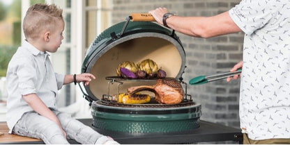 Dezelfde 5-delige Eggspander Kit geplaatst in een Big Green Egg kamado. Doordat het rack op het RVS rooster van de kamado is geplaatst onstaat er een tweede level waarop ook gekookt kan worden. 