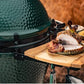 De acacia houten zijtafeltjes bevestigd aan een Big Green Egg. Op het zijtafeltje is een bordje gepaatst met gegrild en gesneden vlees en 2 kommetjes met kruiden.